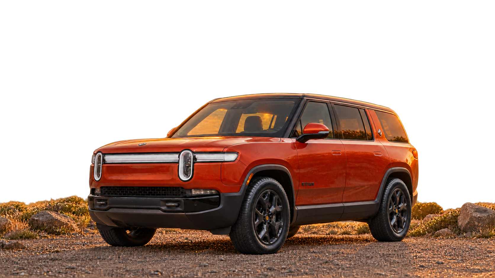Orange Rivian R1S on a coastal drive at sunset